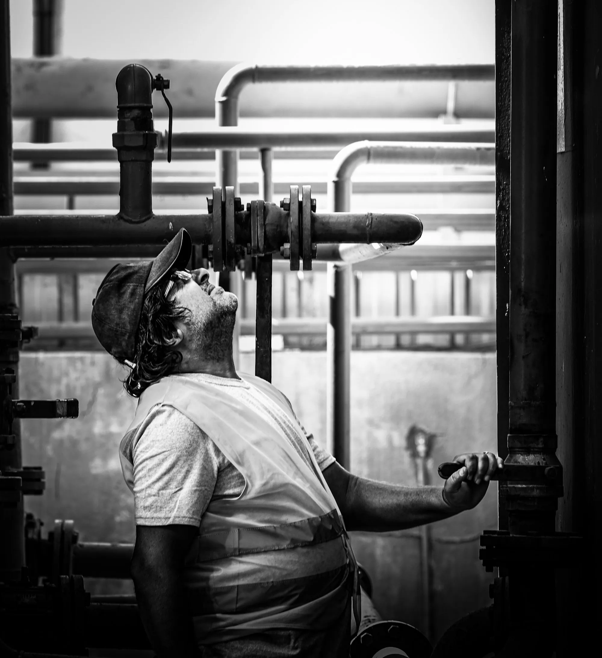 A worker inspecting a run of pipes and valves