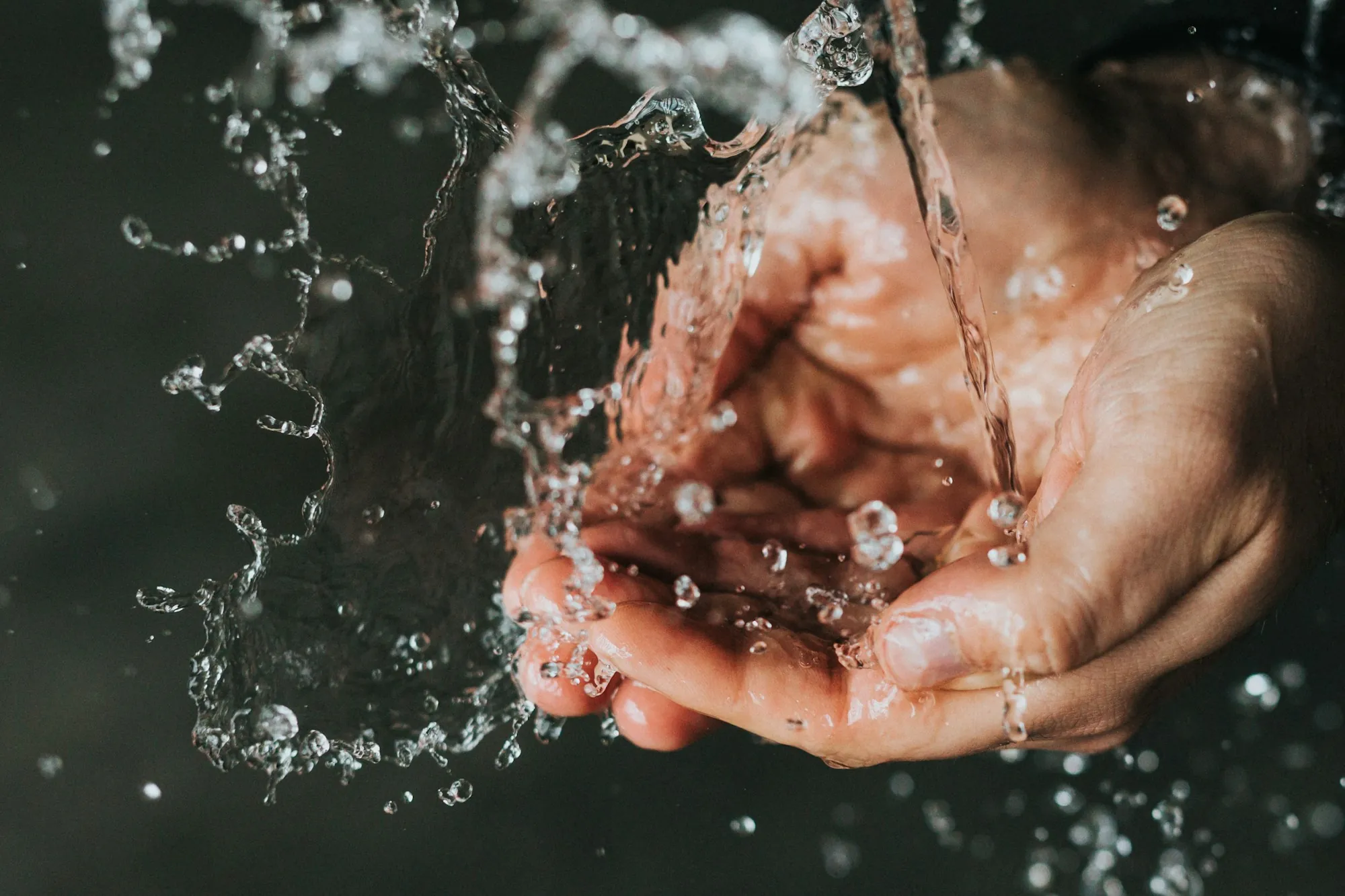 A pair of hands held under a stream of clear water