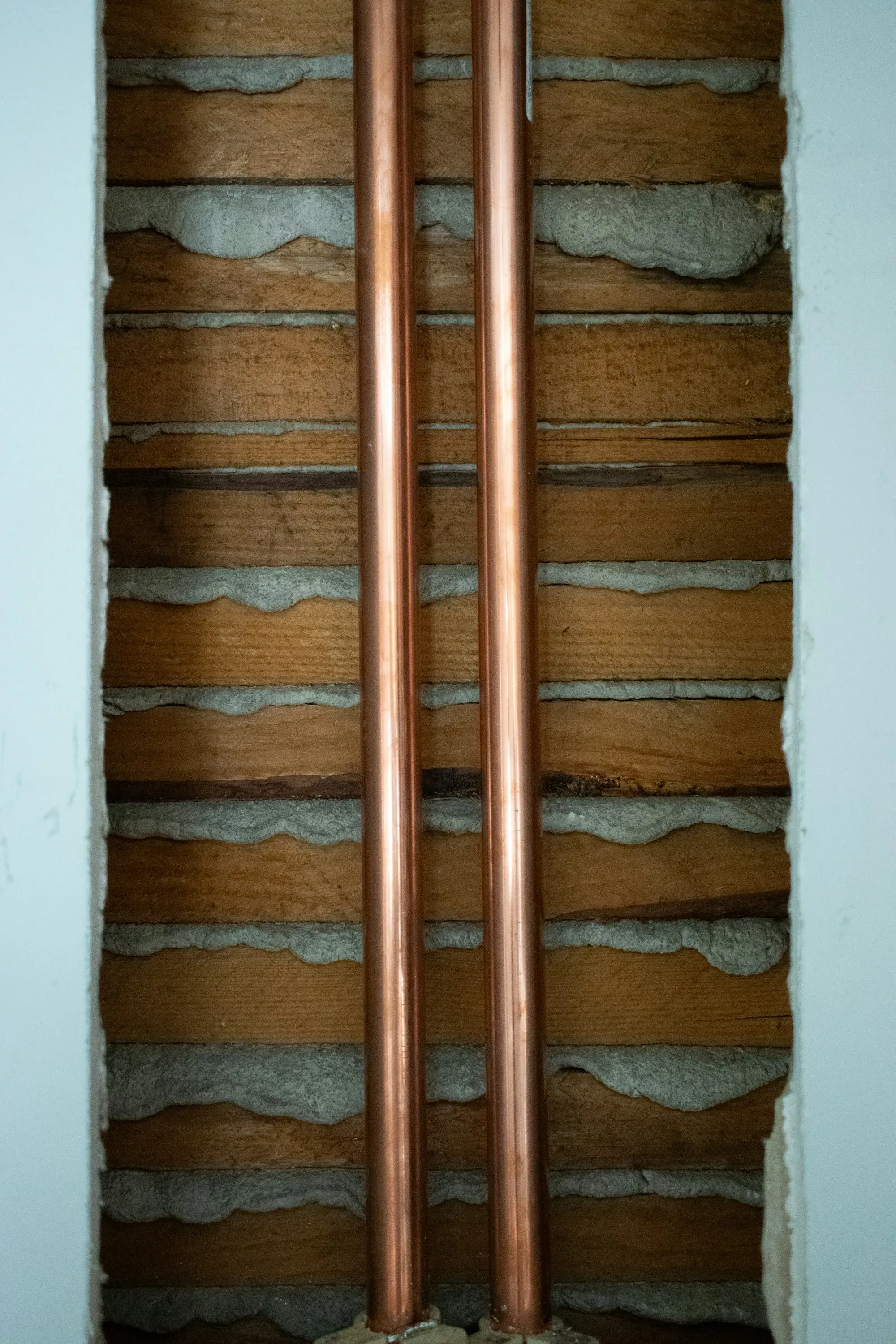 A pair of copper pipes sitting on top of a wall