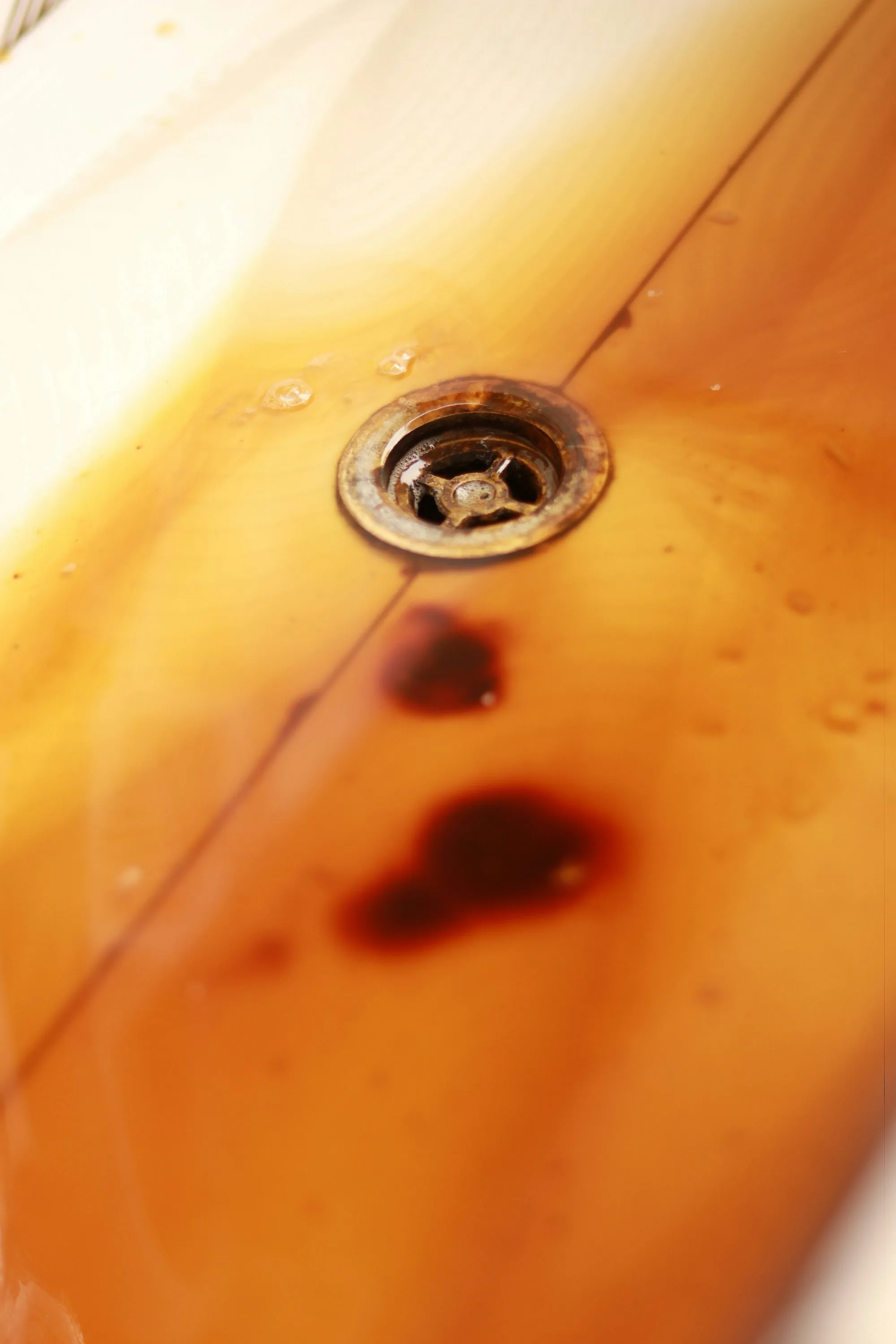 Close-up of a rusted drain in a stained bathtub