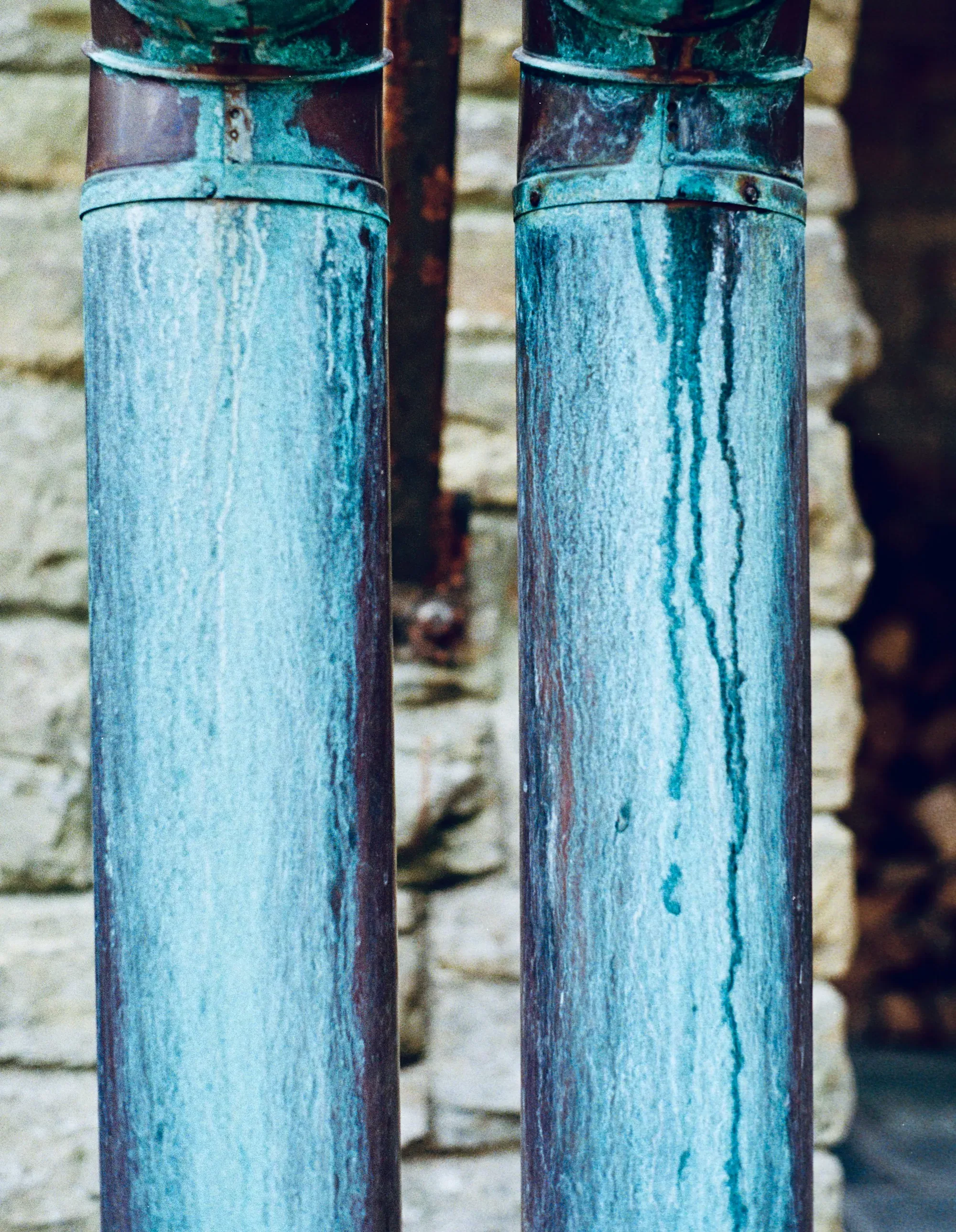 Two metal pipes running beside a brick wall