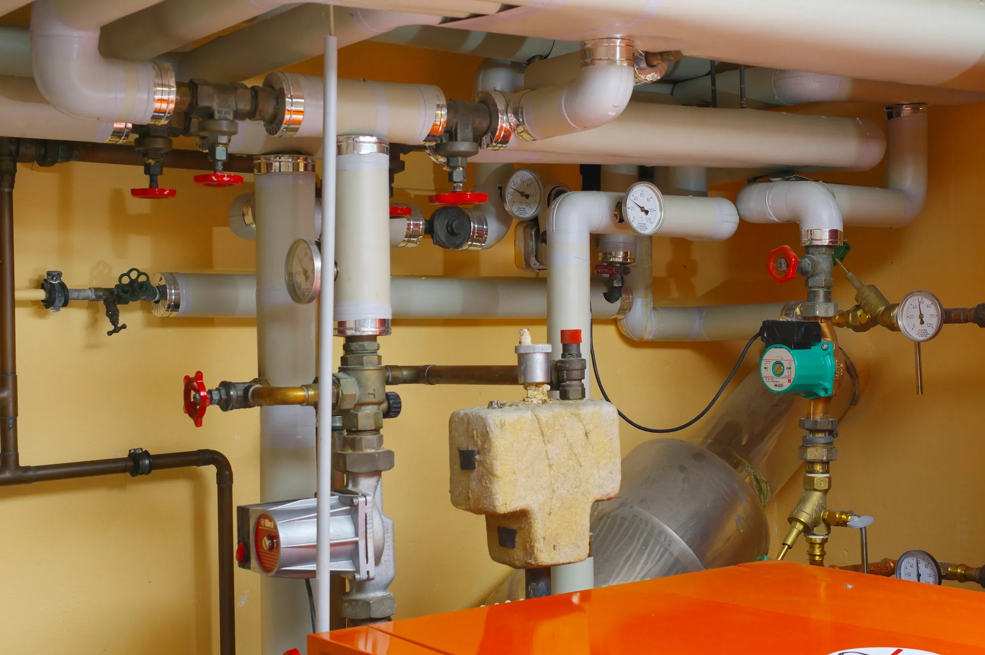 Pipes and valves running across a utility room wall